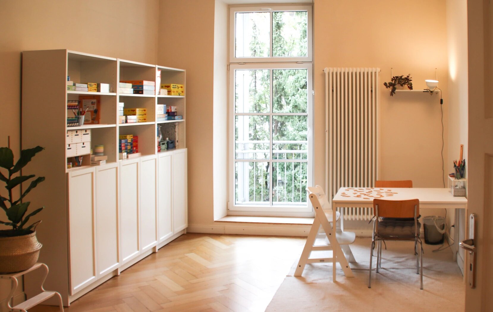 Heller Praxisraum mit Parkettboden, Spieltisch und Blick auf den Balkon